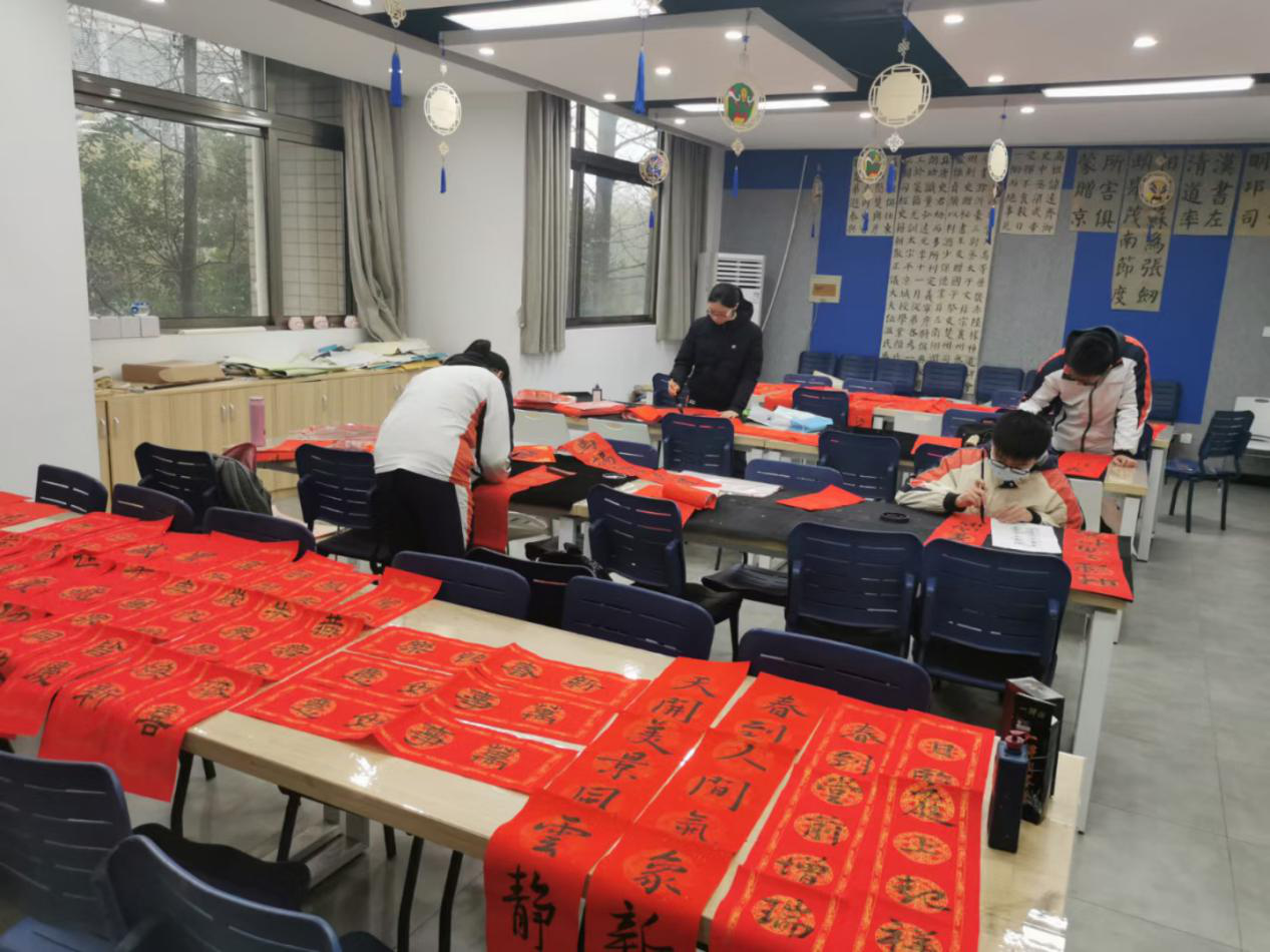 1月26日中午,书法社的社员们在美术教室里热火朝天地张罗着"写春联谢
